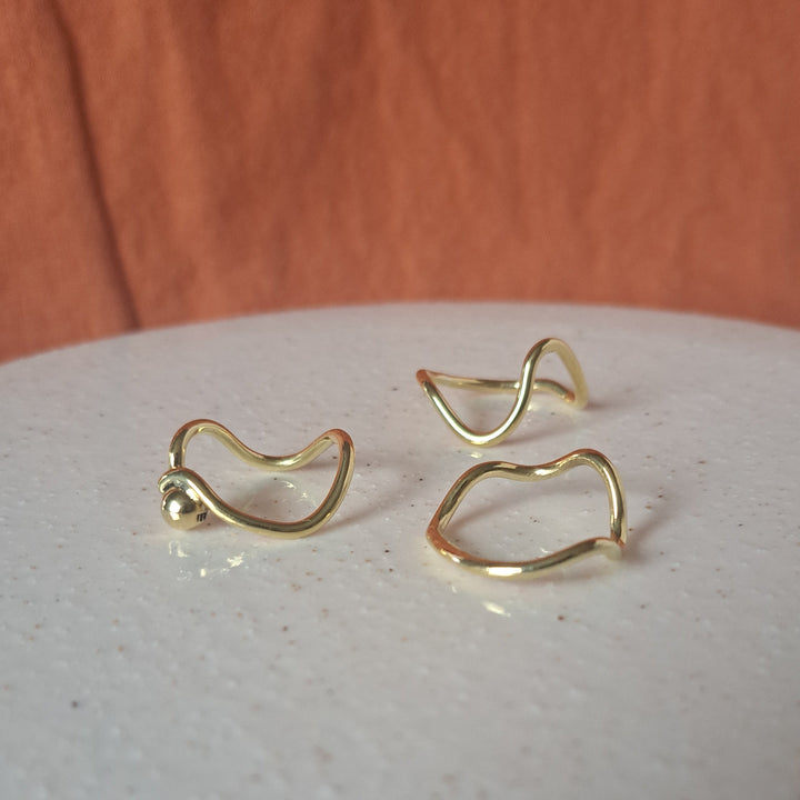 Gold earrings on a textured white surface with a wooden background